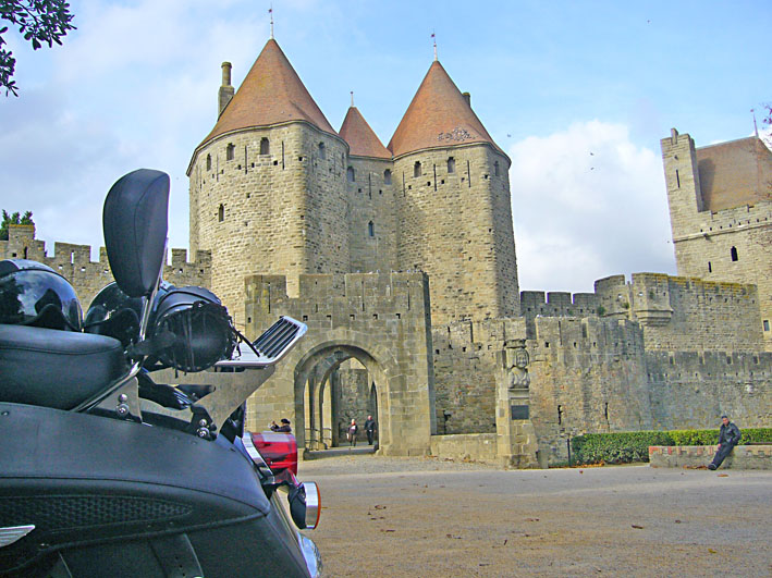Moto garée devant les murailles et les tours de la Cité de Carcassonne