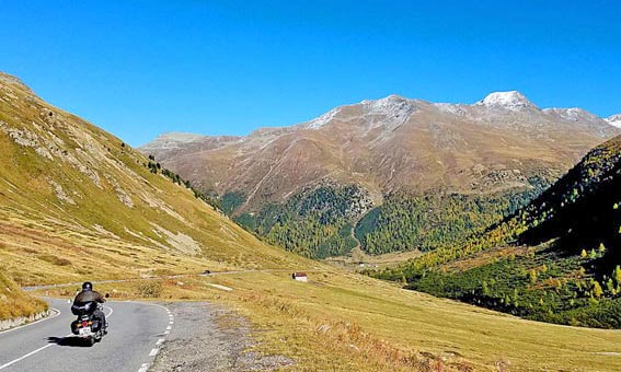 Motard sur une route qui desend dans une vallée vers Livigno (Dolomites)